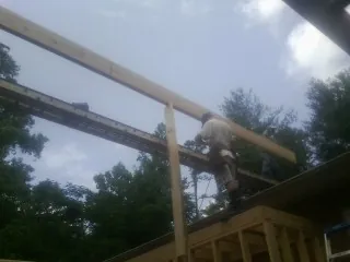 Carpenter setting a ridge beam over a new addition frame — Ice Dam Removal by Roofing Brothers in Wahkiacus