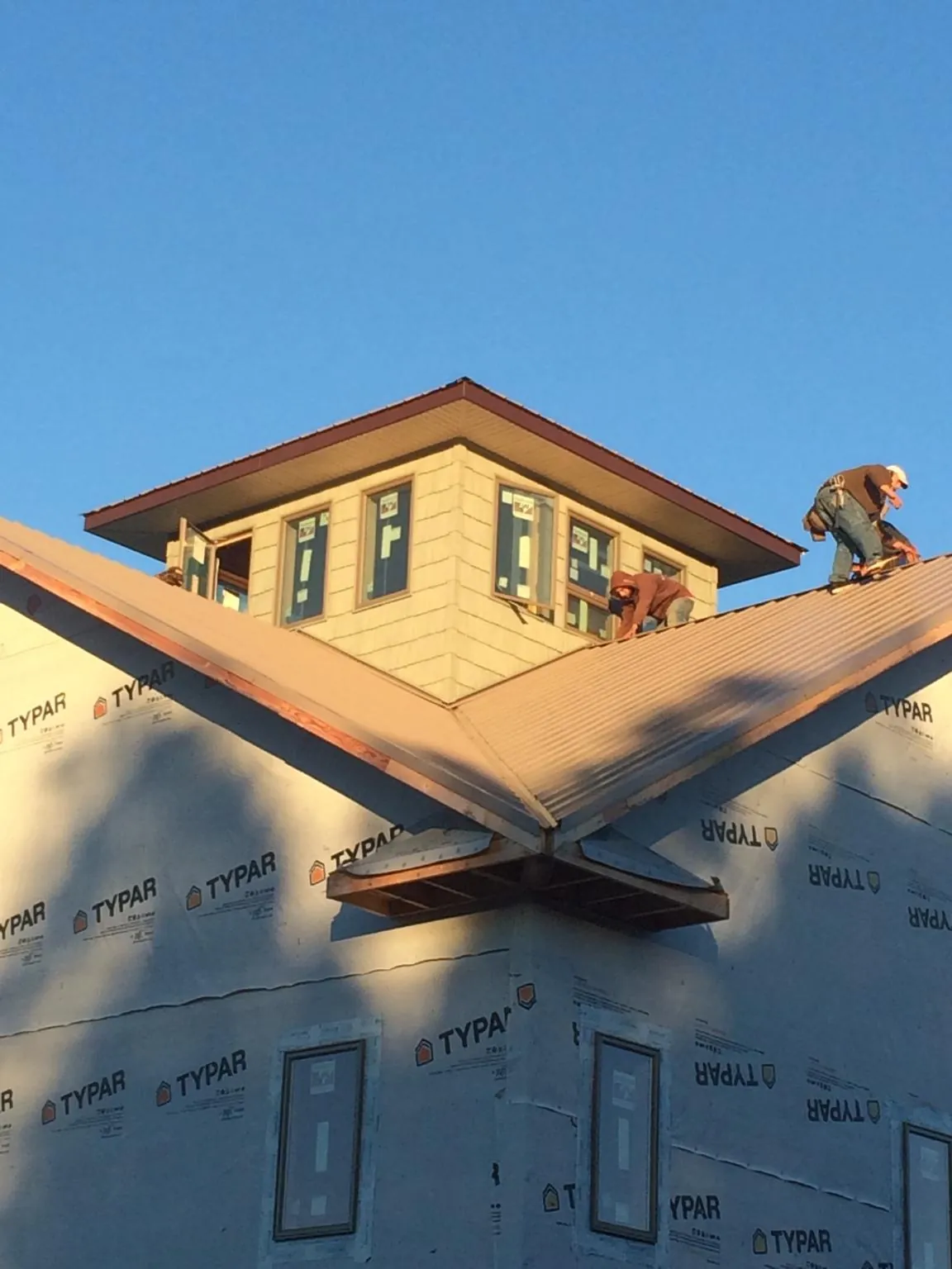 Roofers working around a rooftop cupola on a new metal roof at sunset — Roof Waterproofing in Wahkiacus by Roofing Brothers